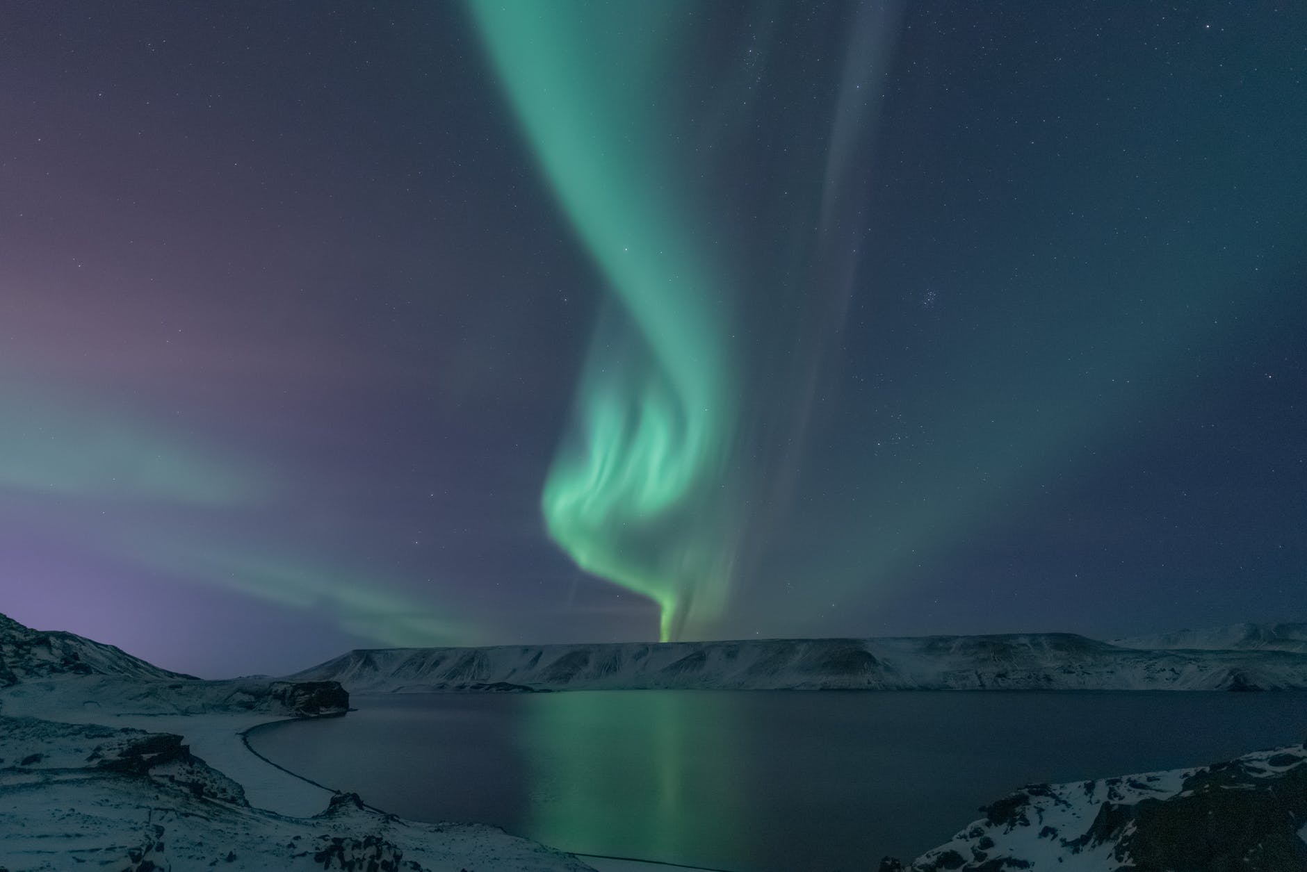 northern lights above lake and snowy landscape