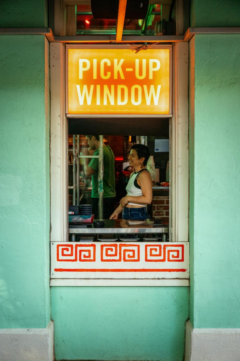 Colorful restaurant pick-up window with a woman waiting in Portland, Oregon.